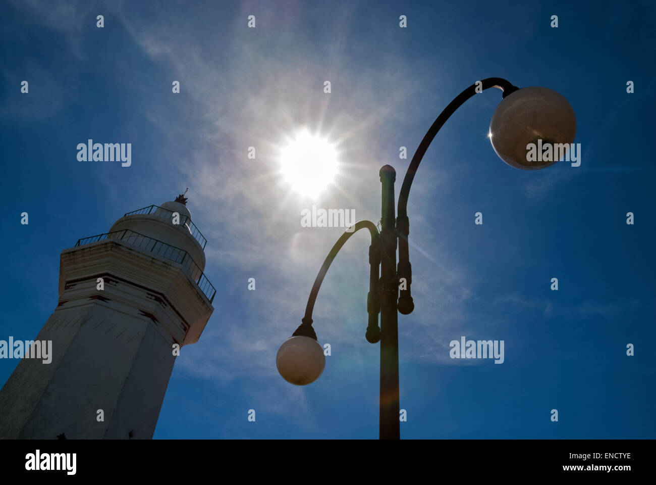 Mosque tower and street lamps silhouetted against the sun. Stock Photo