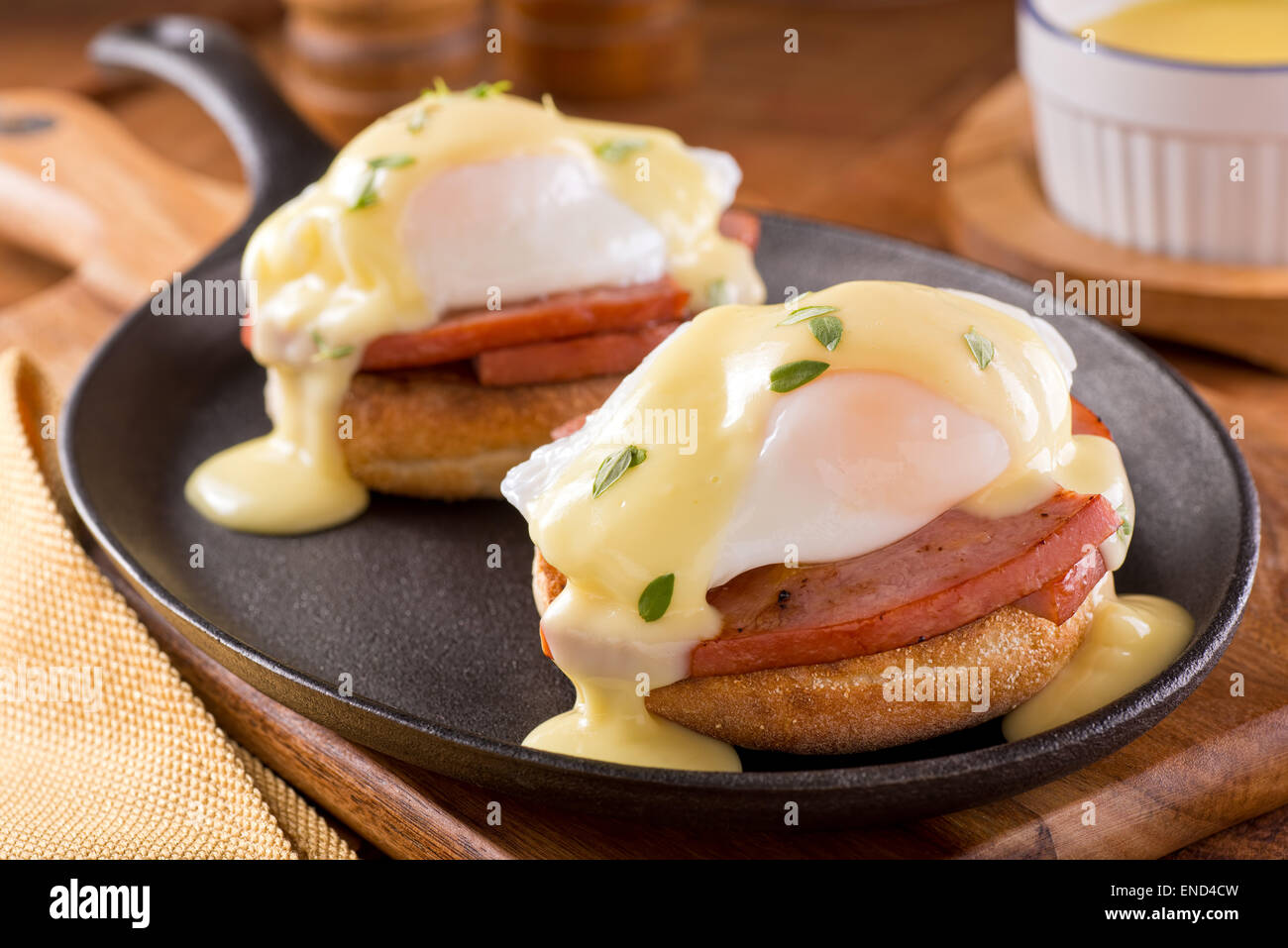 A delicious eggs benedict with thick cut ham, hollandaise sauce, and thyme garnish. Stock Photo
