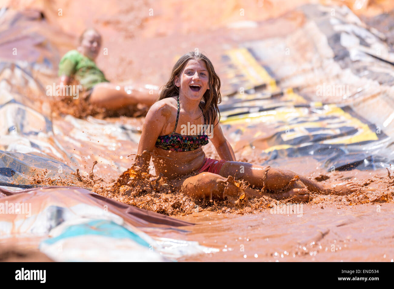 A young girl slips down a mud slide during the 2015 National Red Neck Championships May 2, 2015 in Augusta, Georgia. Hundreds of people joined in a day of country sport and activities. Stock Photo