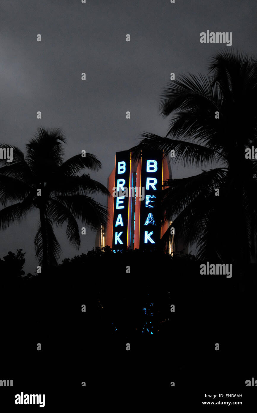 Miami Beach Art Deco hotel at night lit up with neon, framed with palm trees Stock Photo