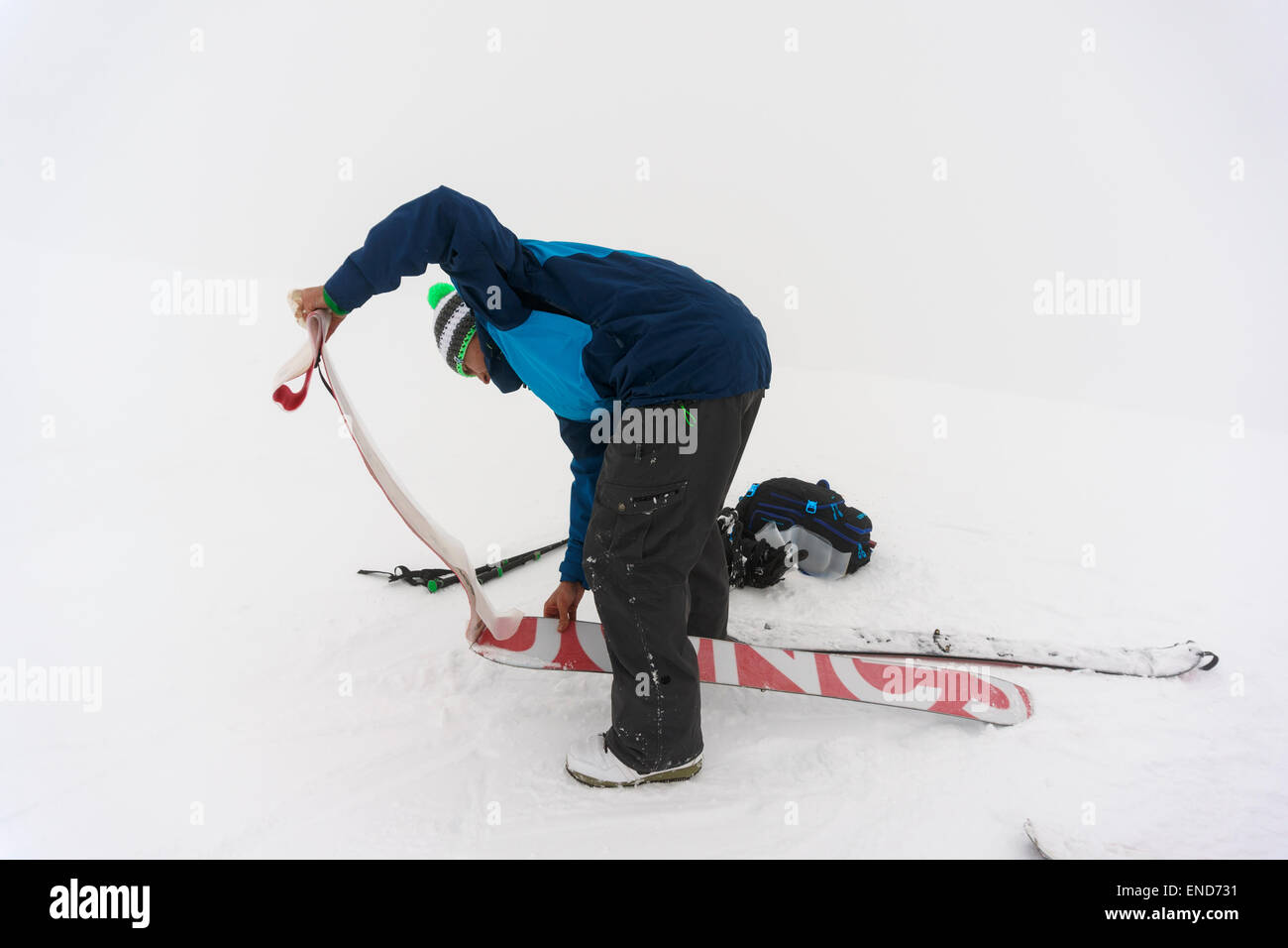 A man removing skins from a splitboard on the summit of Fastdalstinden, Lyngen Alps, Norway Stock Photo