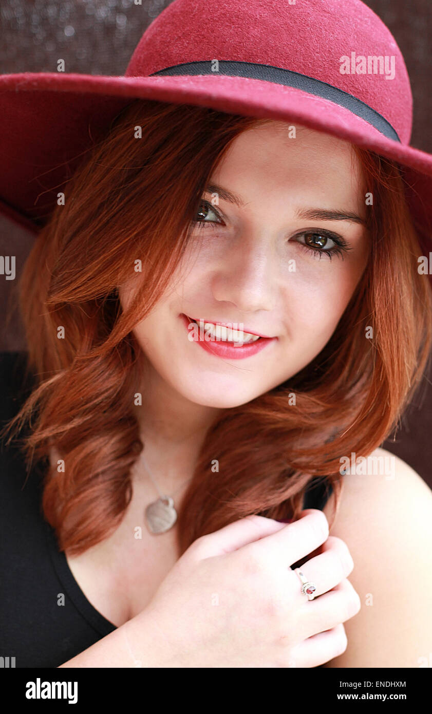 Beautiful young woman with red hair wearing a floppy hat smiling Stock Photo