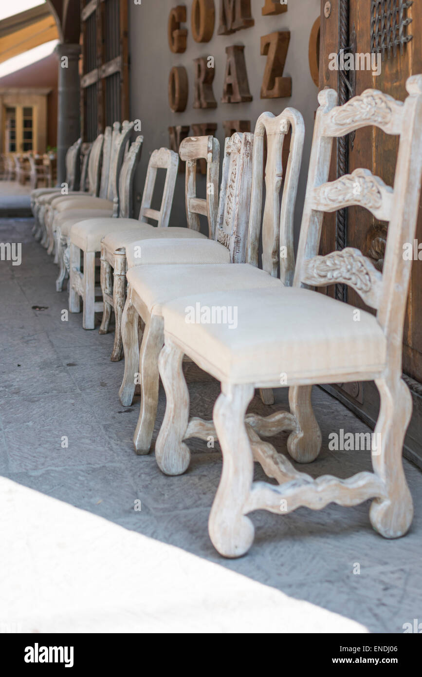 Row of white chairs at storefront in Row of Chairs in San Miguel de Allende in Mexico Stock Photo
