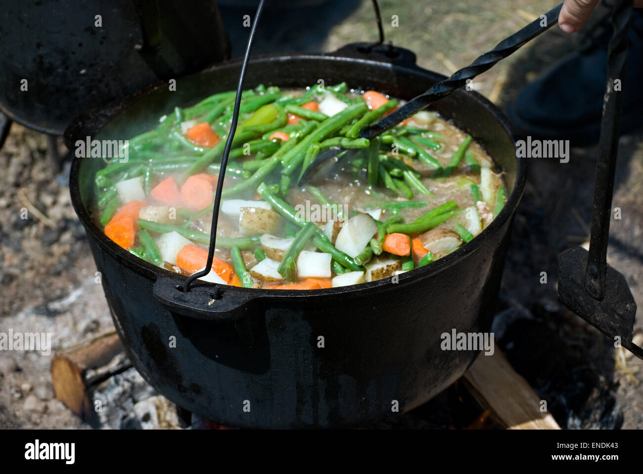 Homemade beef stew simmering in black kettle over an open fire. Stock Photo