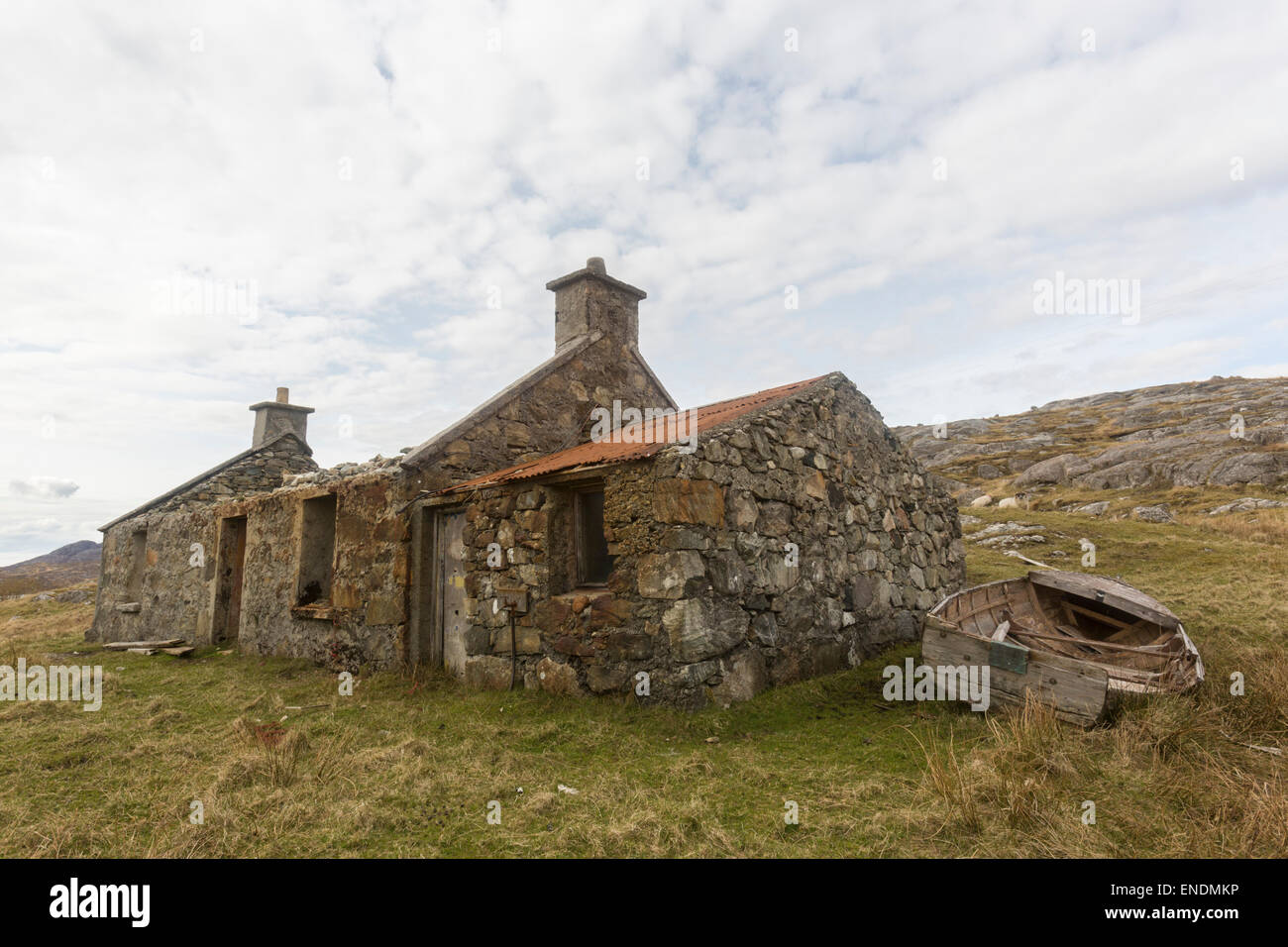 A deserted crofters cottage on the Isle of Harris with a small paddle boat next to it Stock Photo