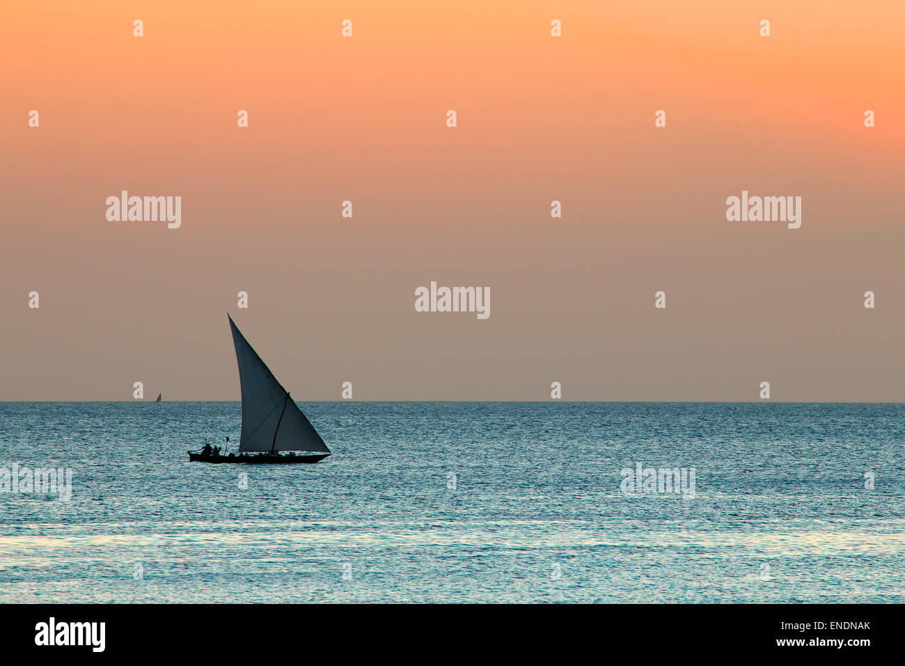 Silhouette of a small sailboat (dhow) on water at sunset, Zanzibar island Stock Photo