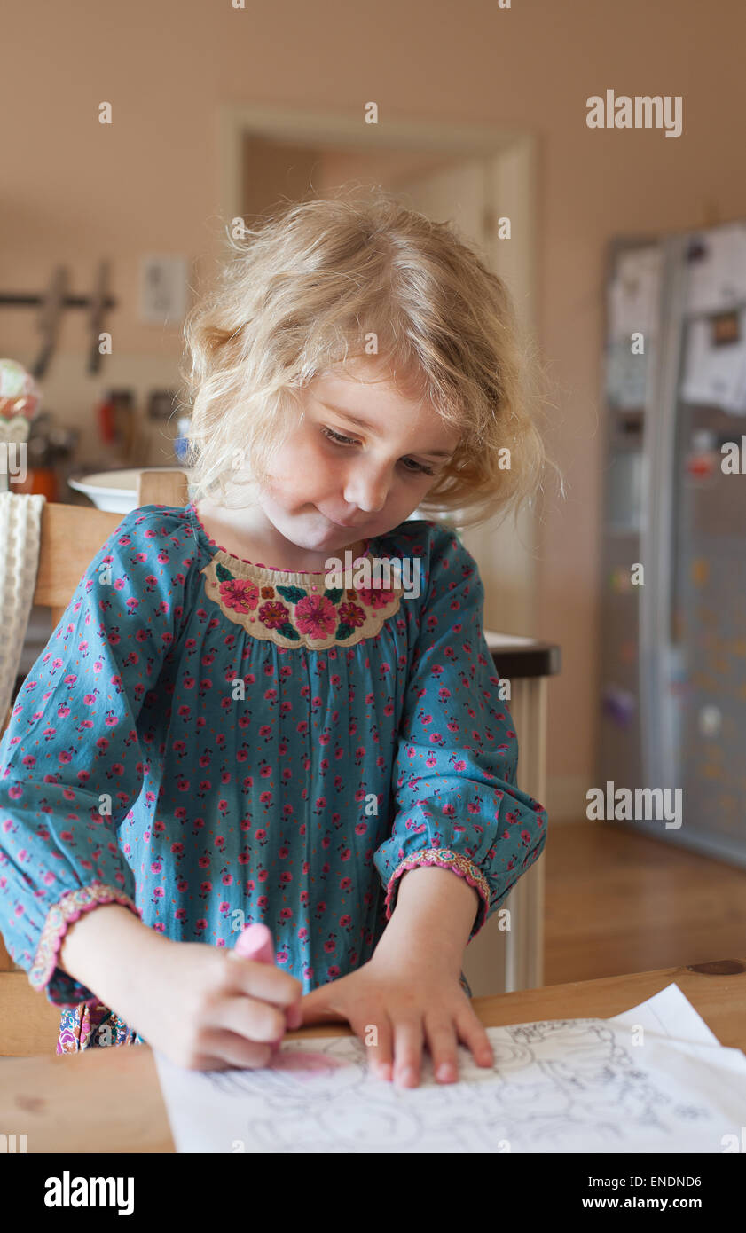 Pretty blond haired girl coloring in at the kitchen table Stock Photo