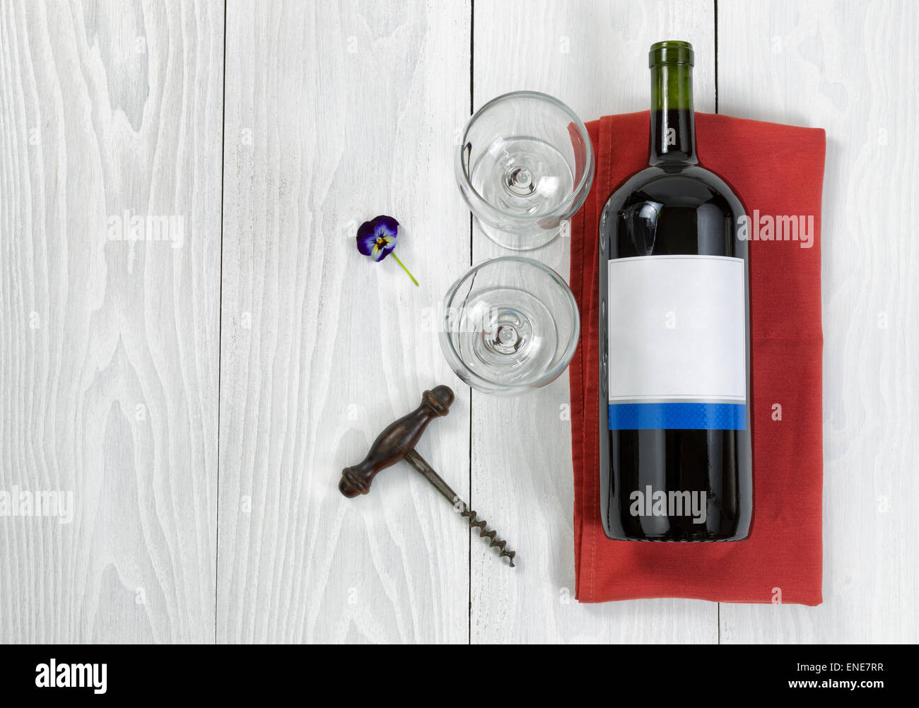 Overhead angled view of a large bottle of red wine, drinking glasses