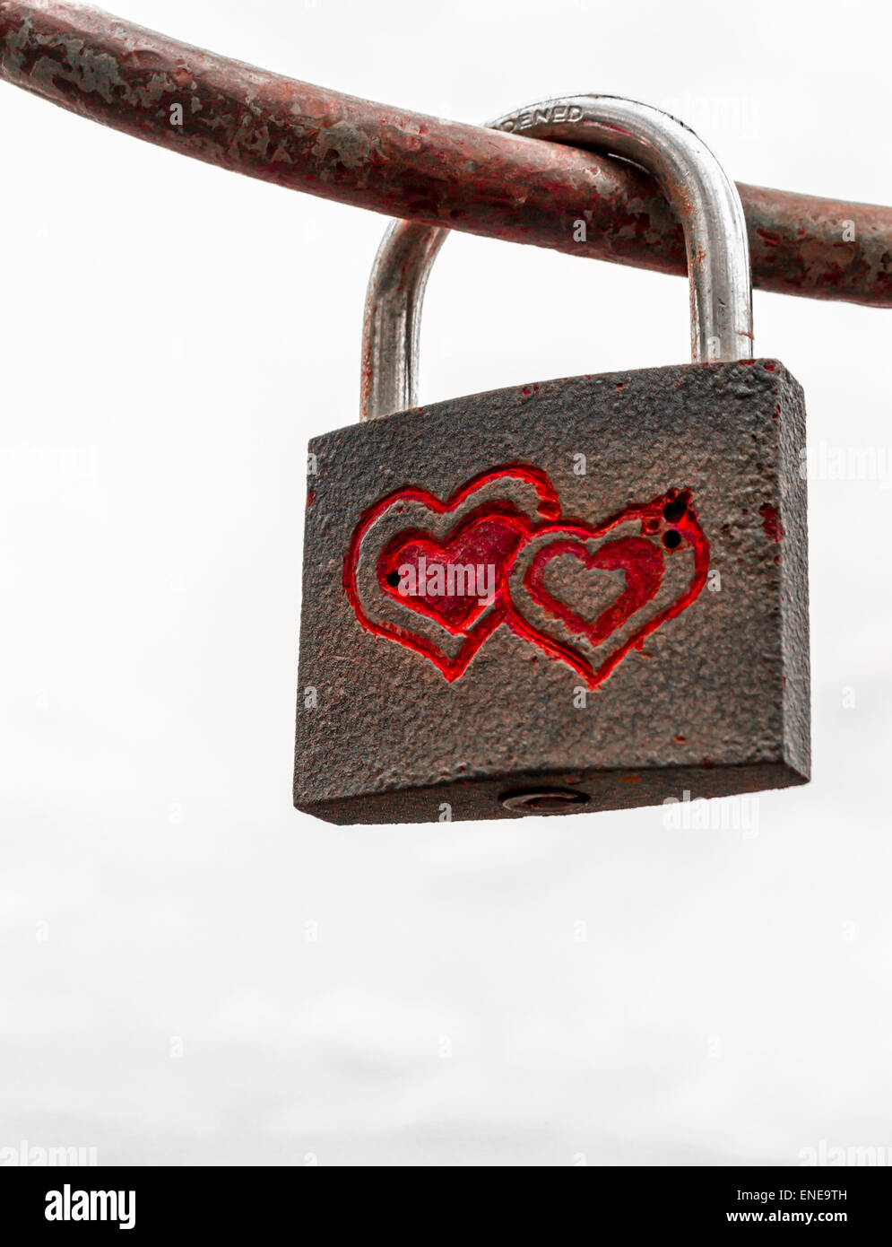 Locked padlock on iron rod with red engraved interconnected love hearts ...
