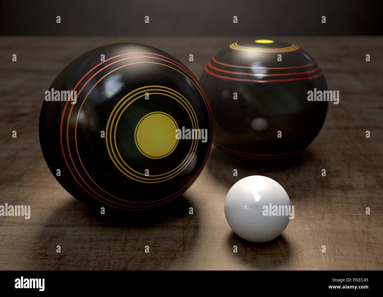 Two wooden lawn bowling balls surrounding a white jack on a wooden isolated dark studio background Stock Photo