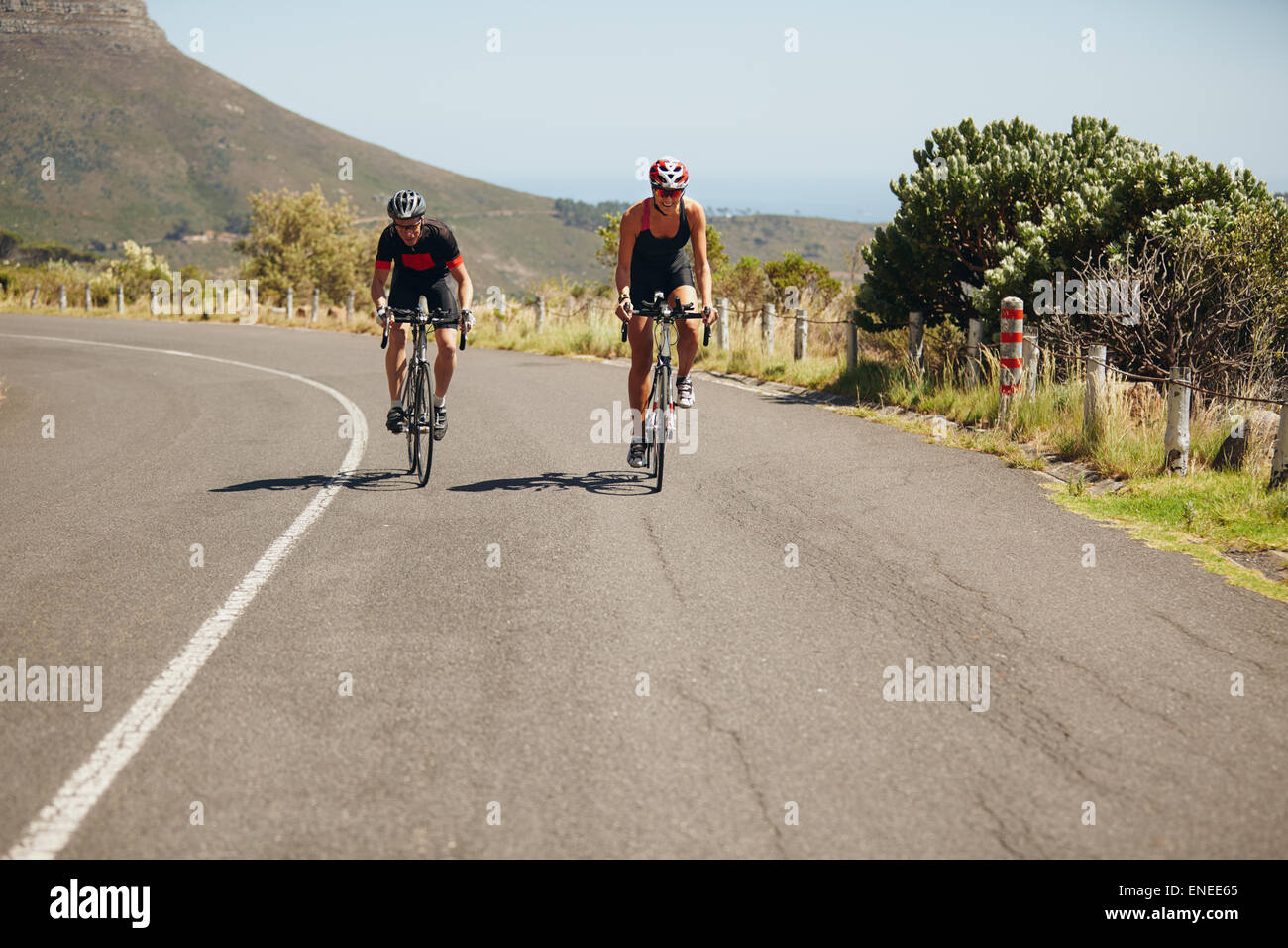 Cyclist riding bikes on open road. Triathletes cycling on bicycles. Practicing for triathlon race. Stock Photo