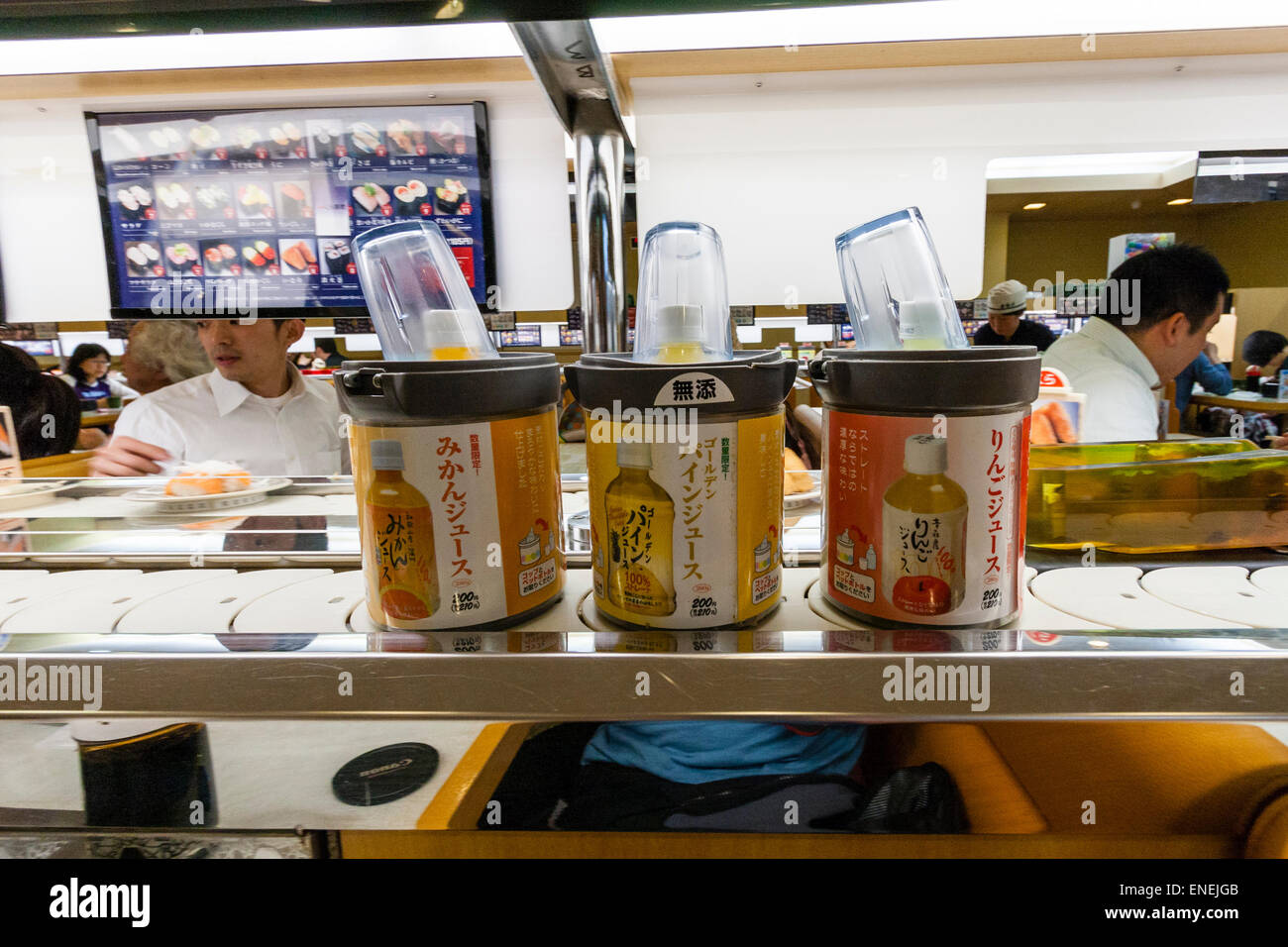 Interior of a typical Japanese conveyor belt sushi restaurant. Close up of three drink cartons moving along the conveyor belt. Stock Photo
