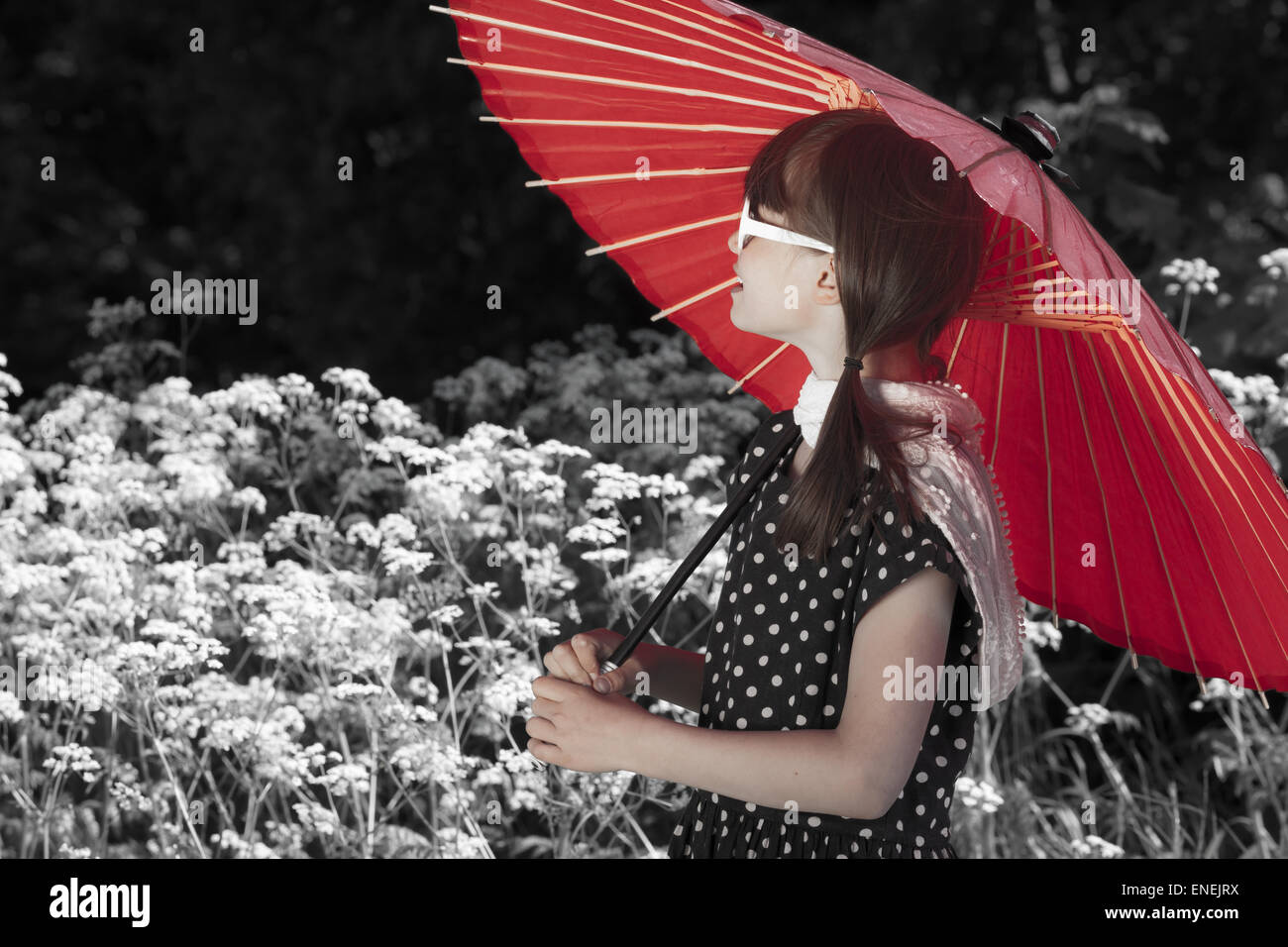 Little retro fashioned girl walks at the park with a red umbrella Stock Photo