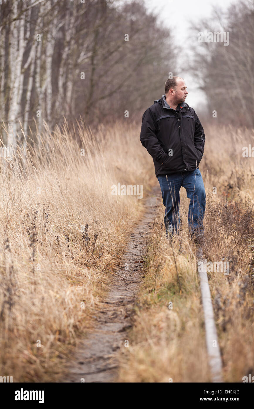Middle aged man is walking along abandoned railway tracks / Looking forward at the Way of Life Stock Photo