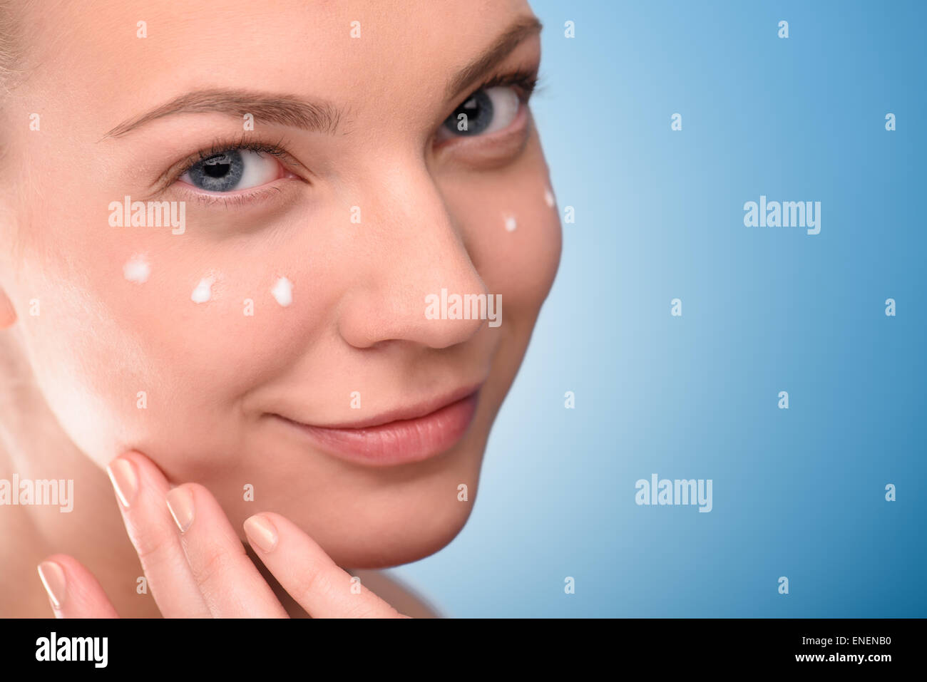 Woman Applying Lifting Cream On Face, Over Blue Background. Close Up ...