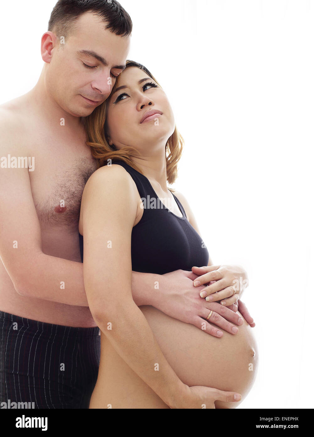 Beautiful future parents: his pregnant Asian wife and a happy husband acting hug together Stock Photo