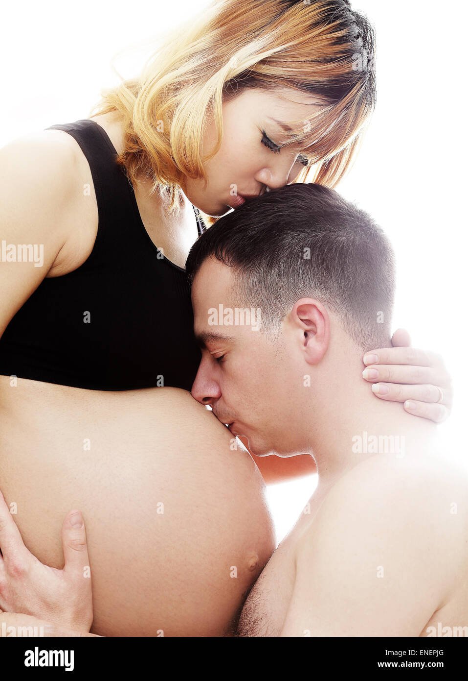 Beautiful future parents: his pregnant Asian wife and a happy husband acting kiss together Stock Photo