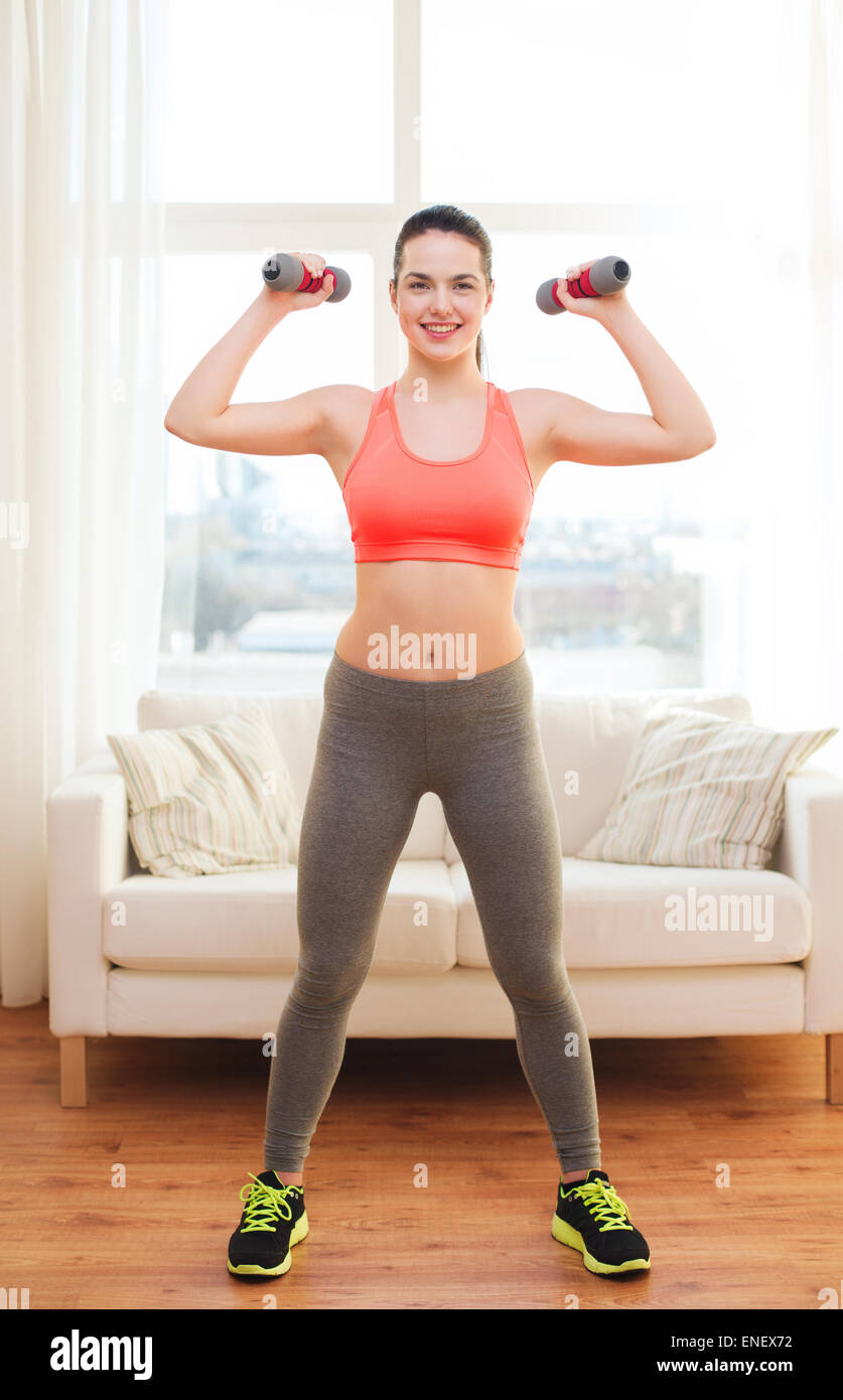 smiling teenage girl exercising with dumbbells Stock Photo