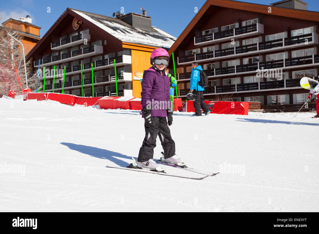 Young girl learning to ski in front of holiday chalets Stock Photo