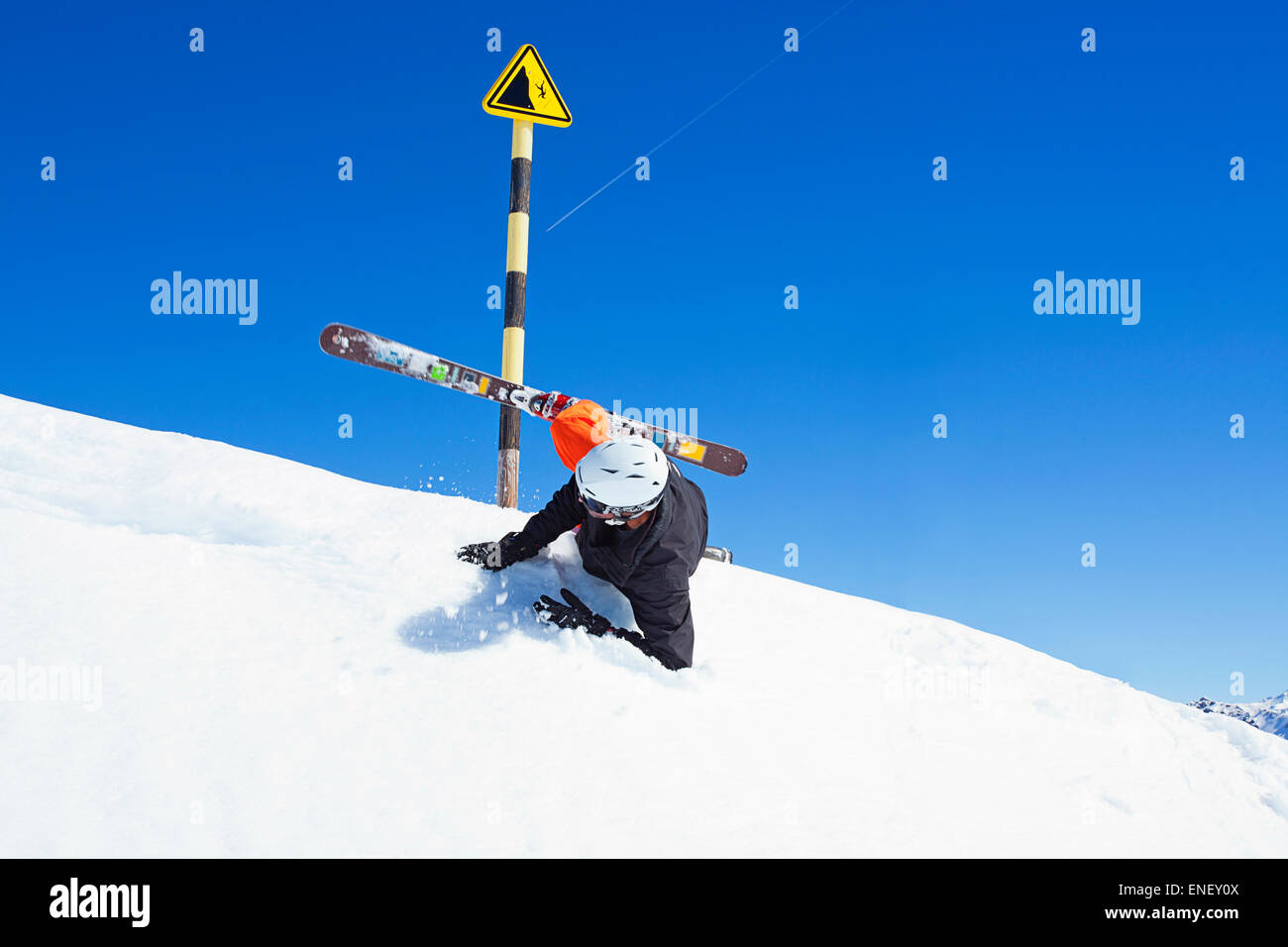 Man falls in front of ski hazard sign in the snow Stock Photo