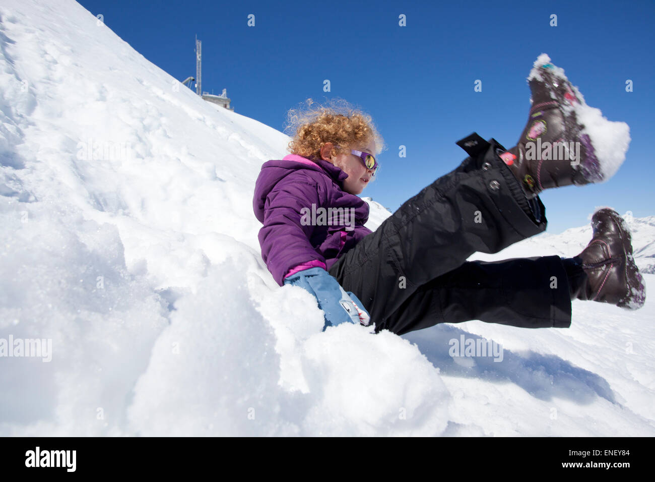 Young girl sliding down snow embankment Stock Photo
