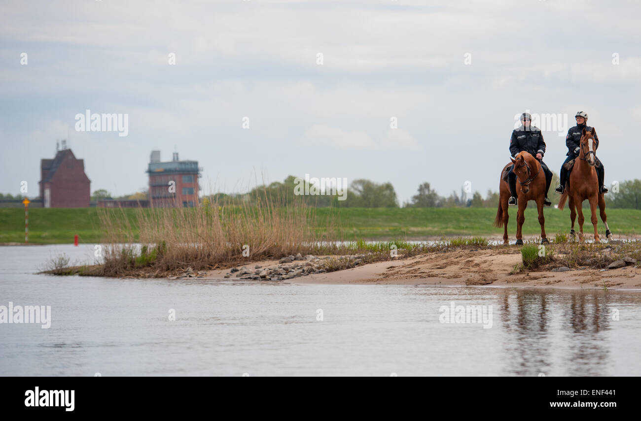 Kaltenhof, Germany. 30th Apr, 2015. Two police officers, Oliver Lenick (L) and Heike Barck, ride their Hanoverian horses, Zbadak and Einstein, near Kaltenhof, Germany, 30 April 2015. Four officers of the riding squad will ensure that visitors of the Niedersächsische Elbtalaue (lit. Lower Saxon Elbe Valley Meadows) biosphere reserve comply with environmental regulations. Photo: Philipp Schulze/dpa/Alamy Live News Stock Photo