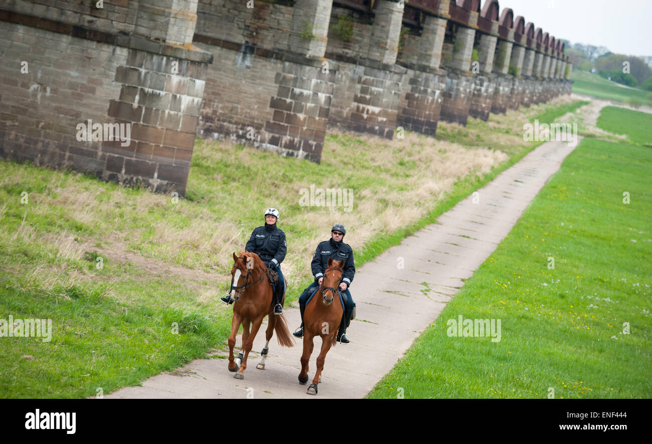 Kaltenhof, Germany. 30th Apr, 2015. Two police officers, Oliver Lenick (R) and Heike Barck, ride their Hanoverian horses, Zbadak and Einstein, near Kaltenhof, Germany, 30 April 2015. Four officers of the riding squad will ensure that visitors of the Niedersächsische Elbtalaue (lit. Lower Saxon Elbe Valley Meadows) biosphere reserve comply with environmental regulations. Photo: Philipp Schulze/dpa/Alamy Live News Stock Photo