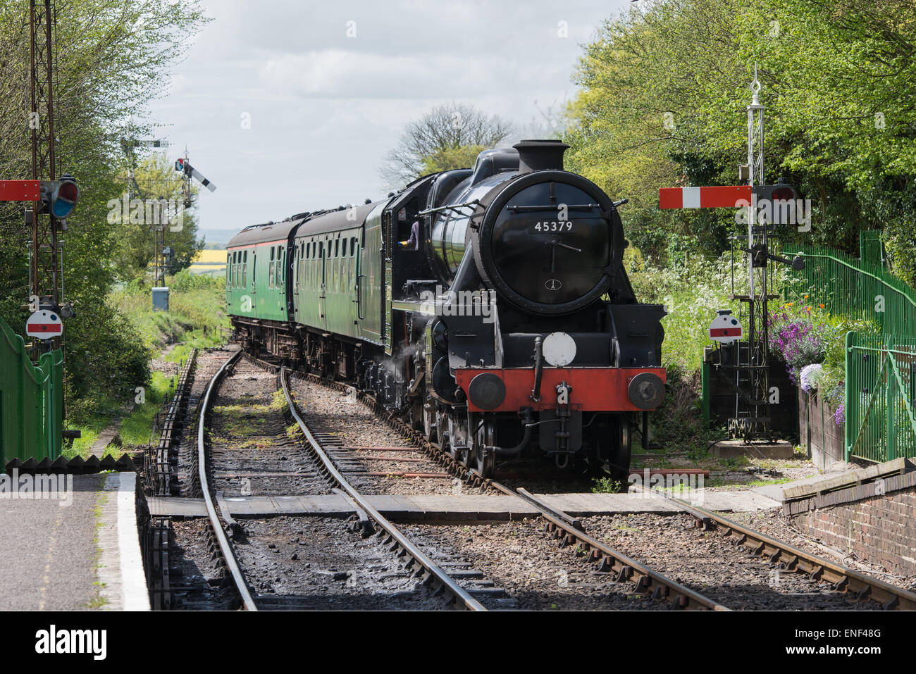 Steam train arriving at railway station on the Watercress heritage railway line on a summer afternoon. Stock Photo