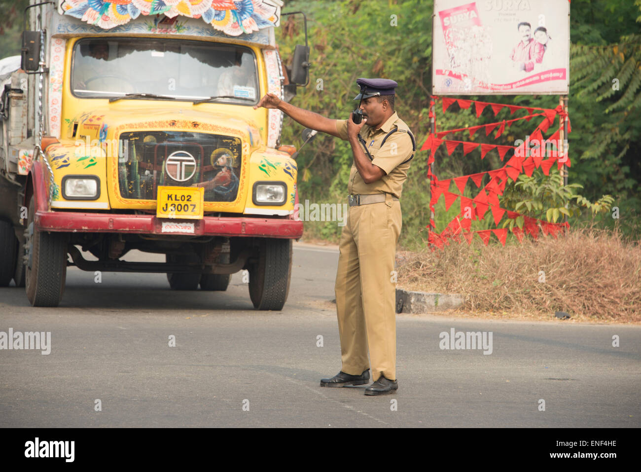 A traffic Police officer trying his best to control the flow of disorganised traffic at a busy cross-road in Kochi, Kerala, India Stock Photo