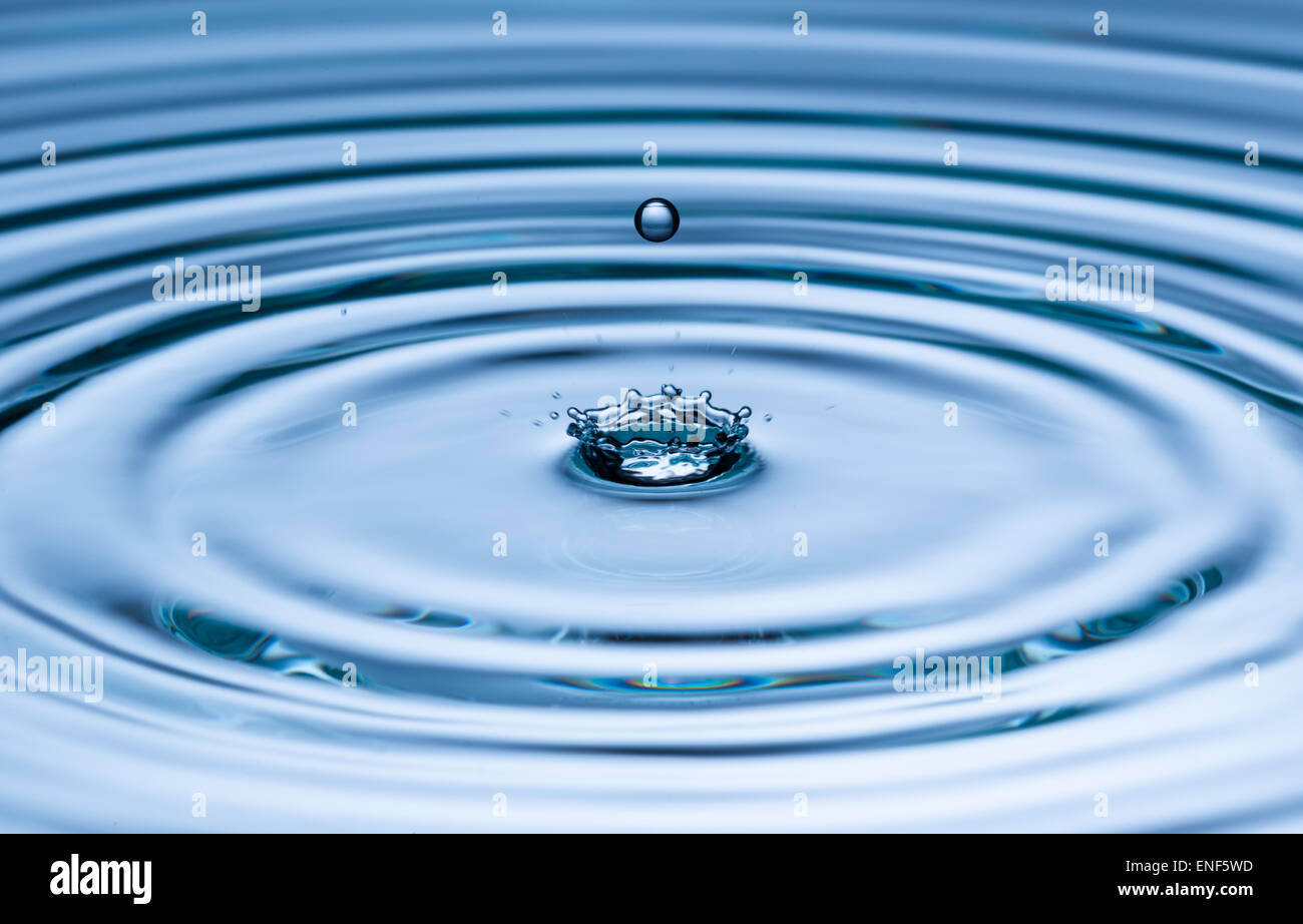 Drop of water falling into water surface, macro photo Stock Photo