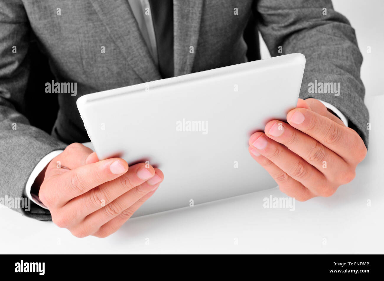 closeup of a young caucasian businessman in gray suit sitting at his office desk uses a tablet computer Stock Photo