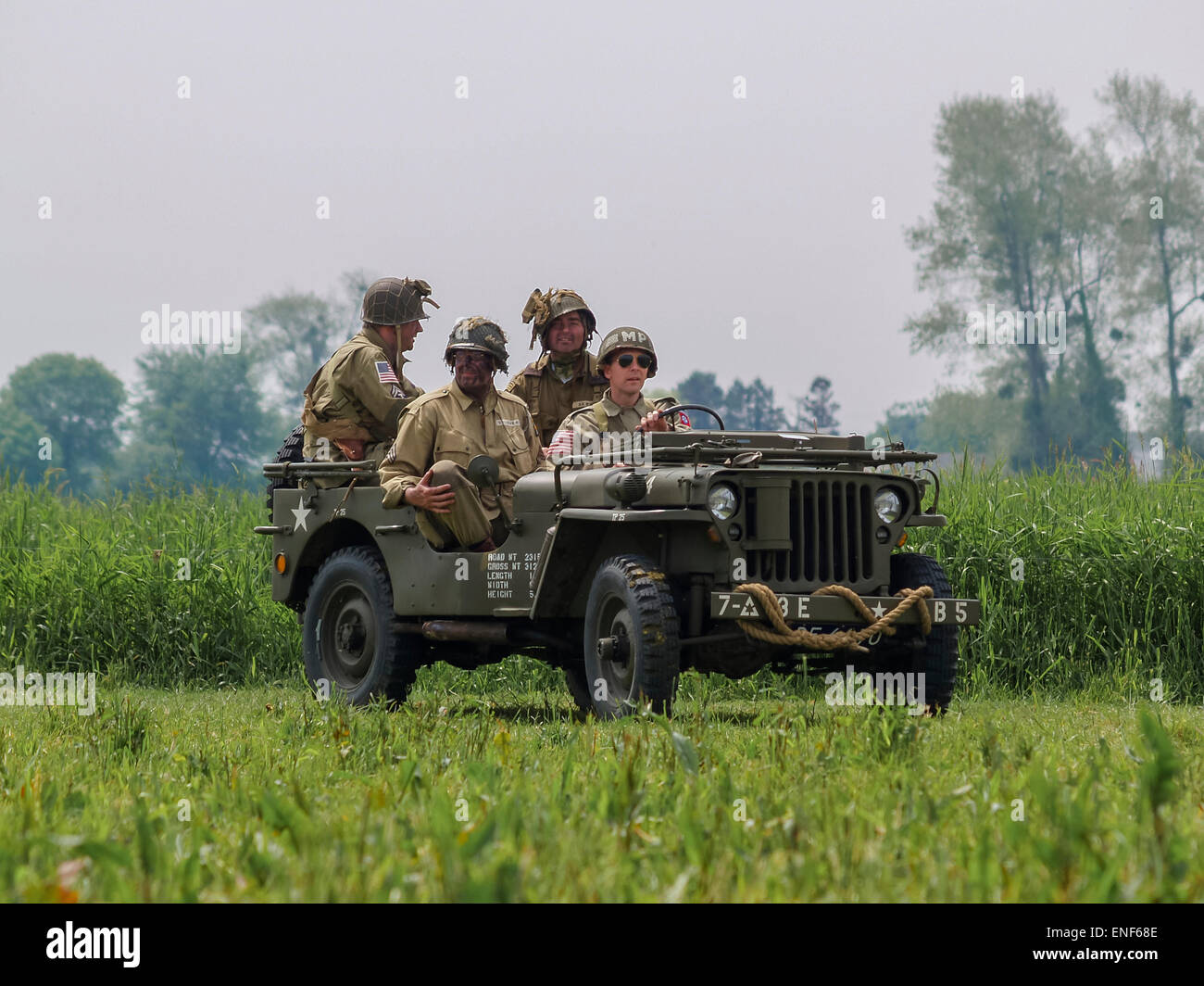 American US Allied Soldiers in WW2 Uniform seated in a Willys Jeep in a meadow as part of the D-Day Anniversary, Normandy France Stock Photo