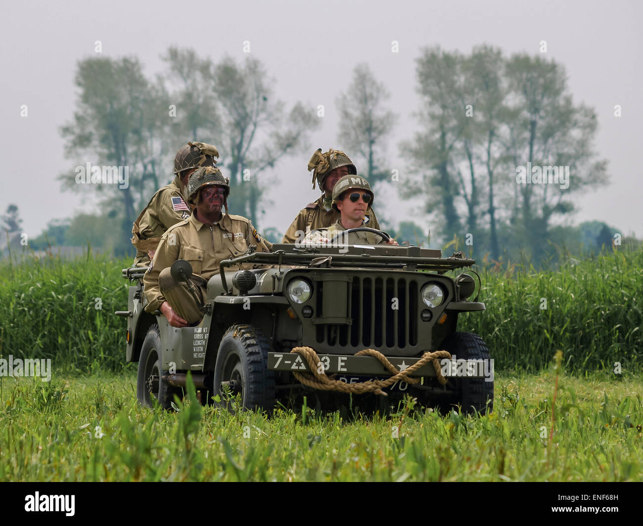 American US Allied Soldiers in WW2 Uniform seated in a Willys Jeep in a meadow as part of the D-Day Anniversary, Normandy France Stock Photo