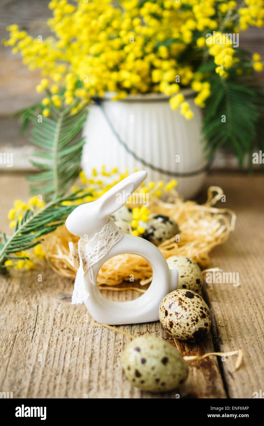 Easter time, Hand decorated Easter Eggs and speckled birds eggs in straw with a branch of colorful yellow clusters of mimosa flo Stock Photo