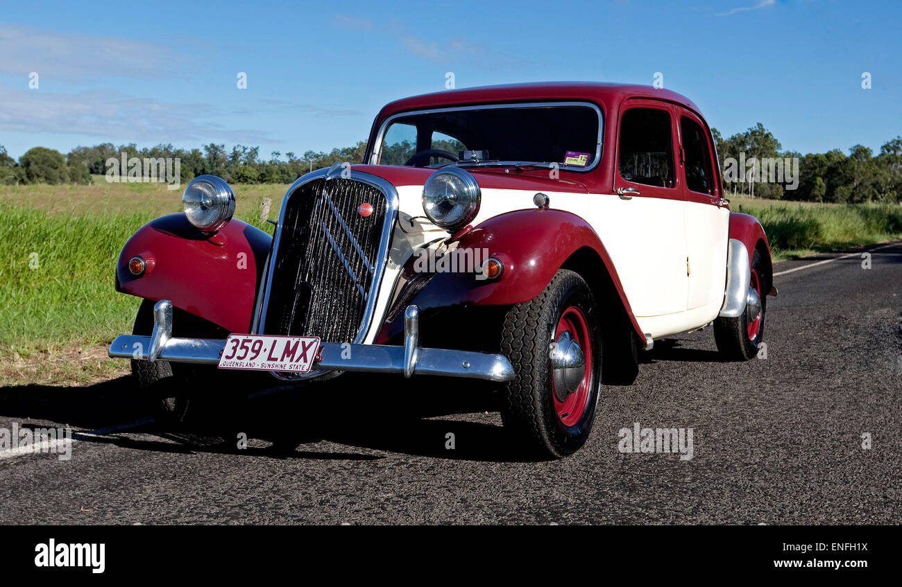 Citroen 1950s big 15 classic car restored, with red and cream gleaming paintwork, on road beside field of green grass Stock Photo