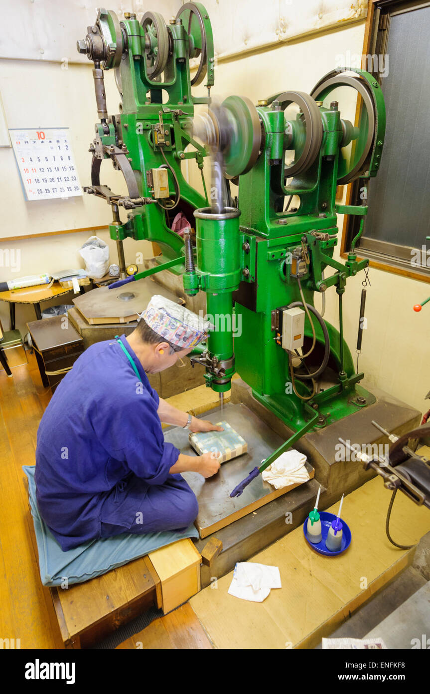 Kanazawa kinpaku: elderly worker uses an old machine to compound gold to produce gold leaf, known in Japan as kinpaku. Traditional craft of Kanazawa. Stock Photo