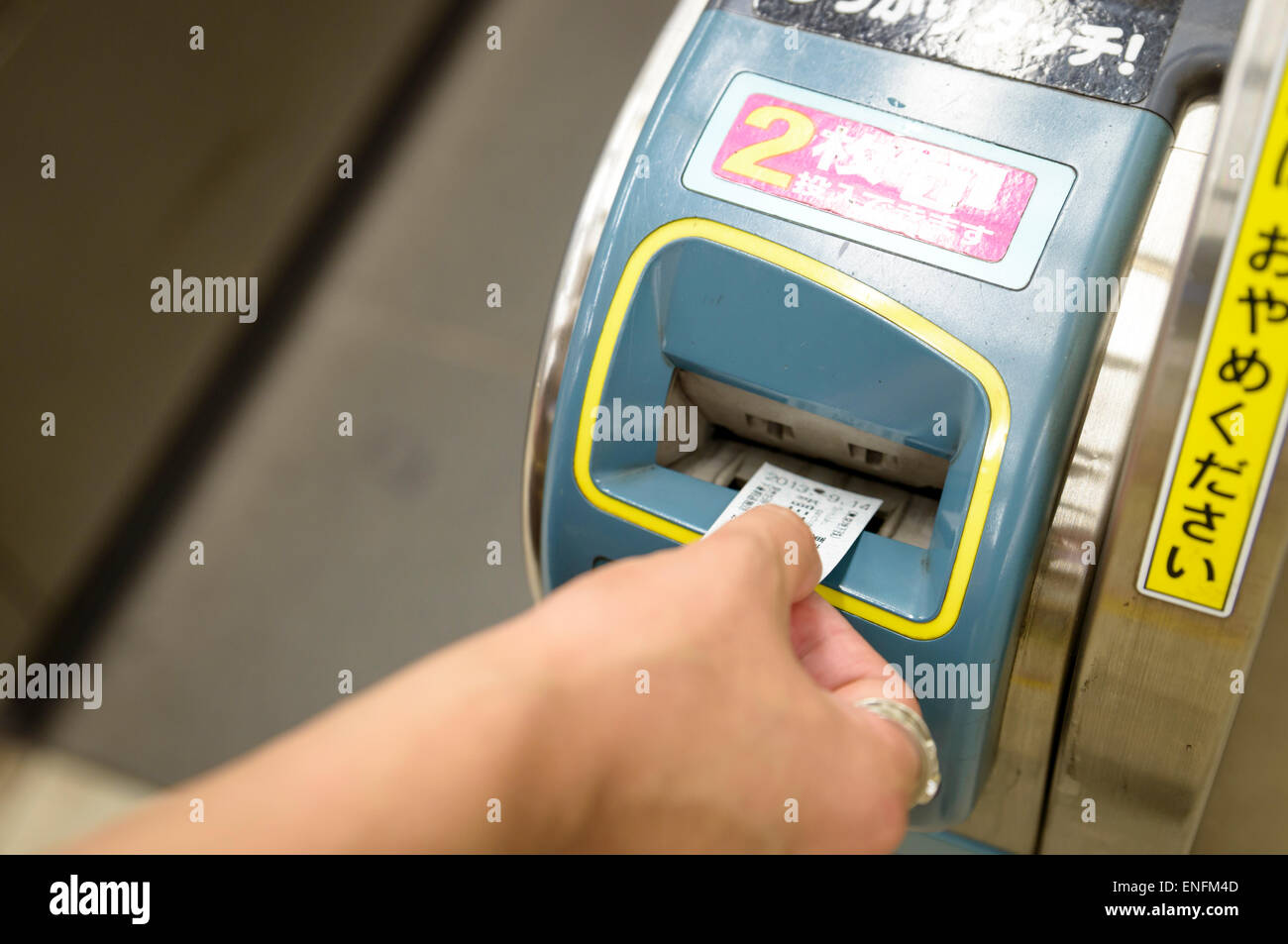 Hand inserting train ticket into ticket gate/turnstile in Japan. Japanese automation. Stock Photo