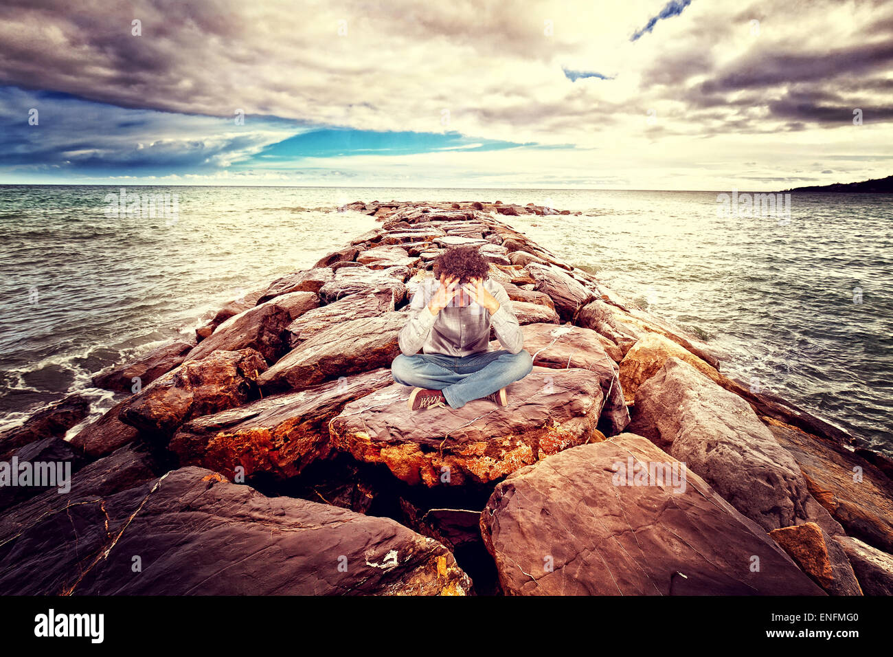 desperate man sit on sea rock Stock Photo