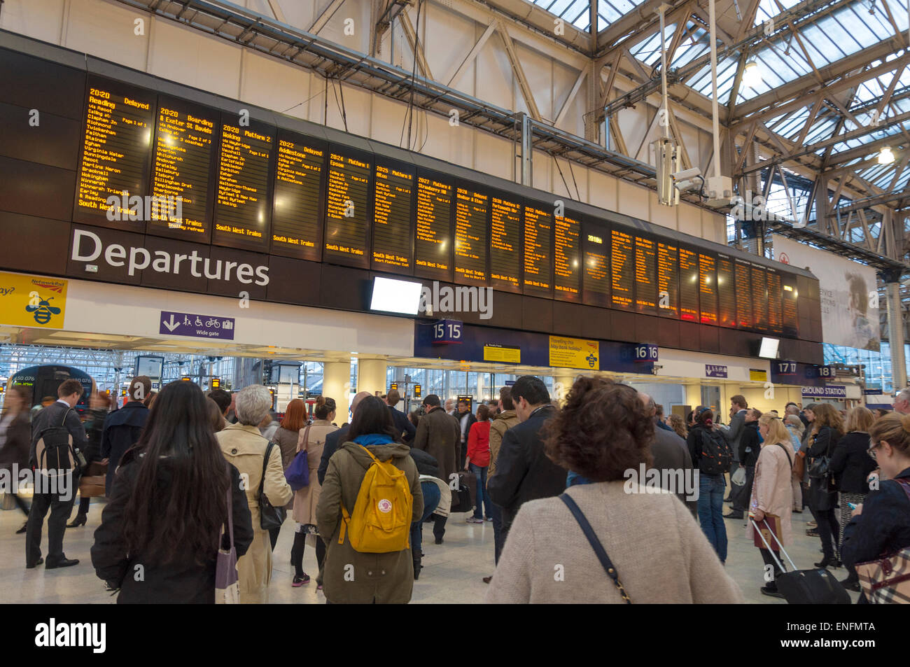 Commuters passengers look at train departure board at London Waterloo railway station Stock Photo