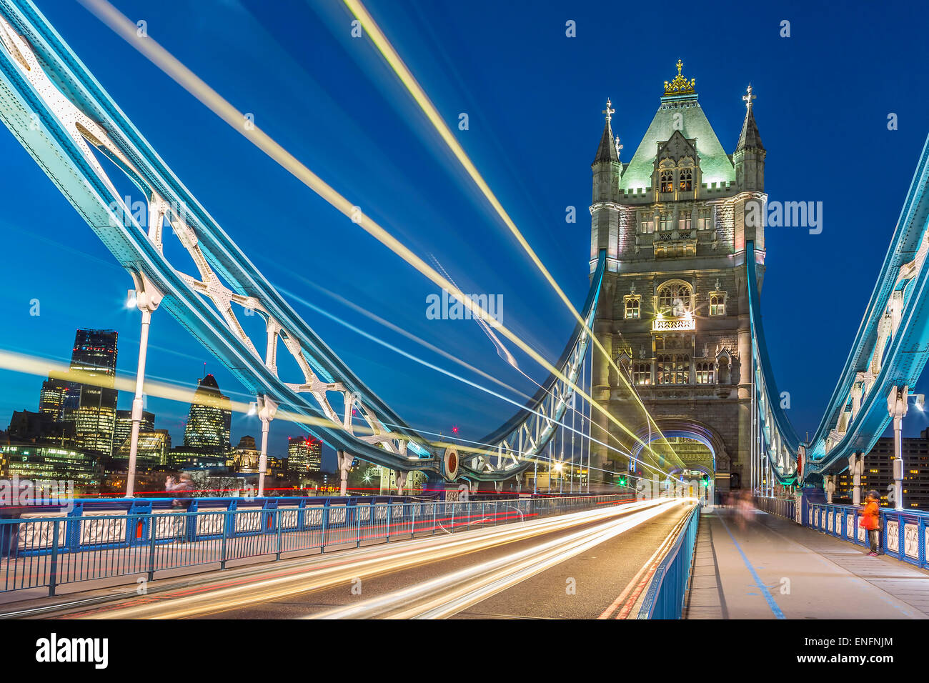 Tower Bridge in London at night with moving red double-decker bus leaving light traces Stock Photo