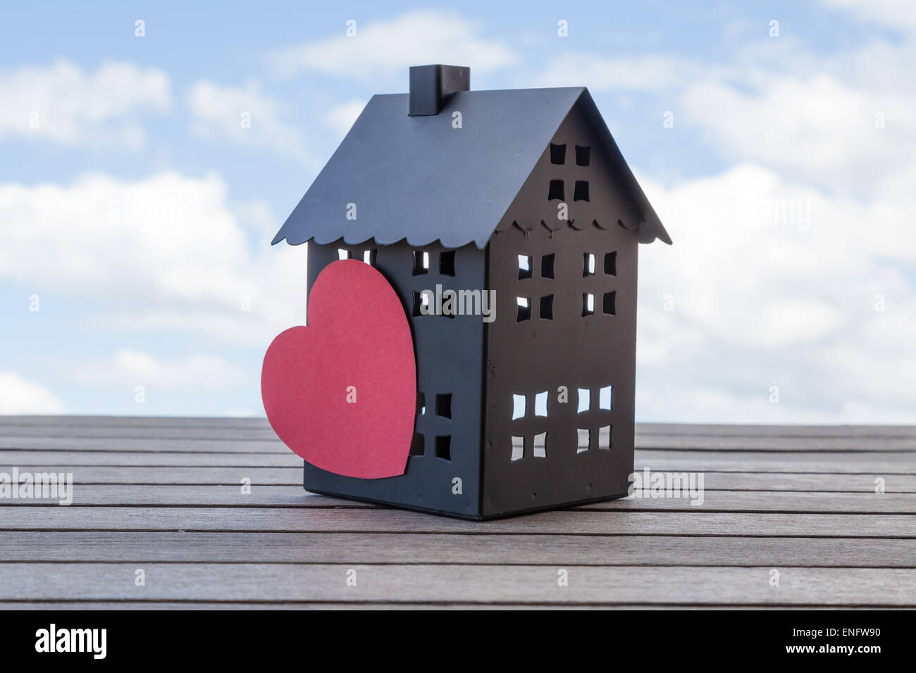 Black house with a heart and a blue sky in the background. Suitable for concepts such as house sales and broker. Stock Photo