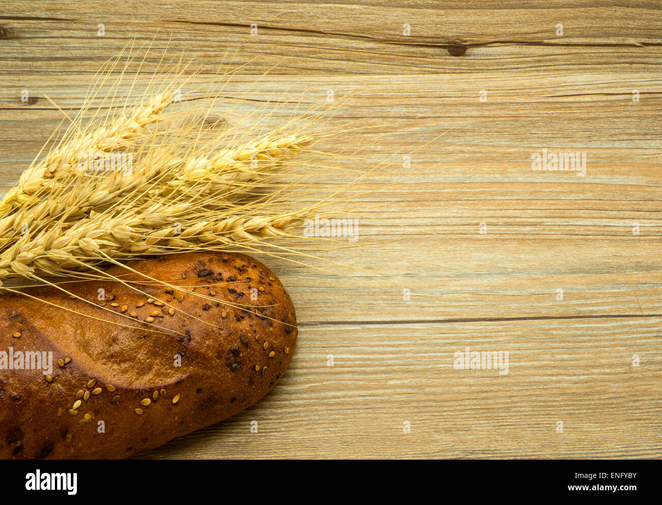 Bread with sesame seeds and ears on a wooden background. Stock Photo
