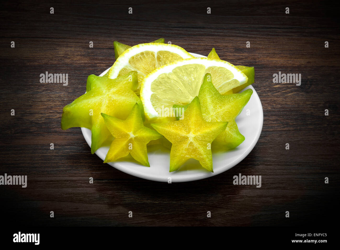 Carambola and lemon on dark brown wooden background. Stock Photo