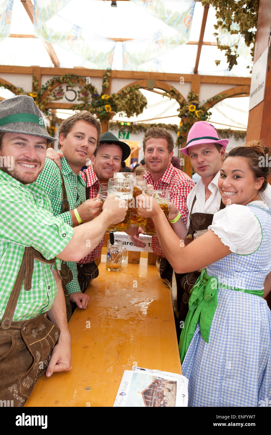 Visitors sit in the tent at the Oktoberfest and drink beer in a beer mug Stock Photo