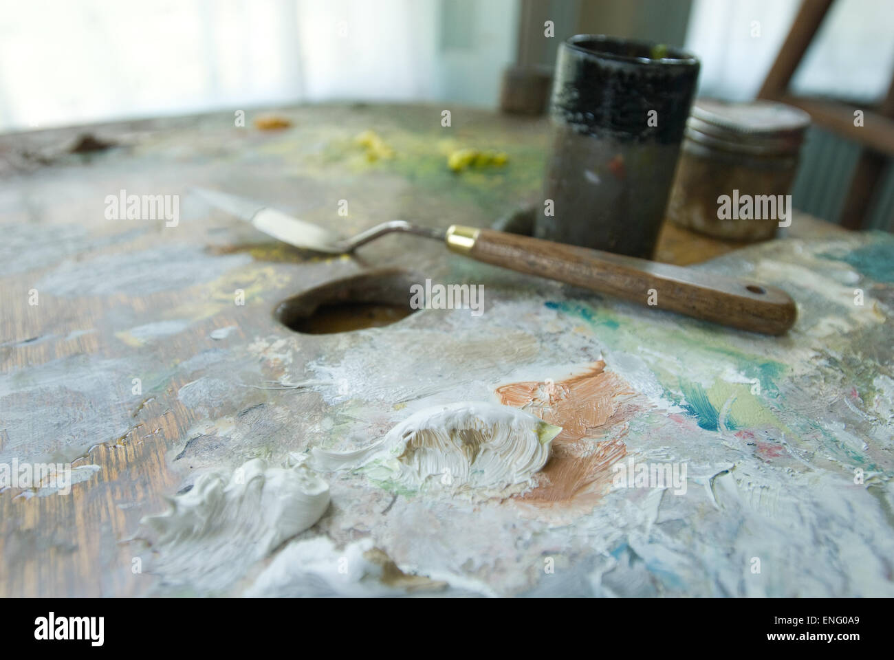 Mixed Oils White Paint On Large Pallet With Painters Knife And Hint Of Studio In Background Mixed Oils White Paint On Large Pallet With Painters Knife And Hint Of Studio In Background