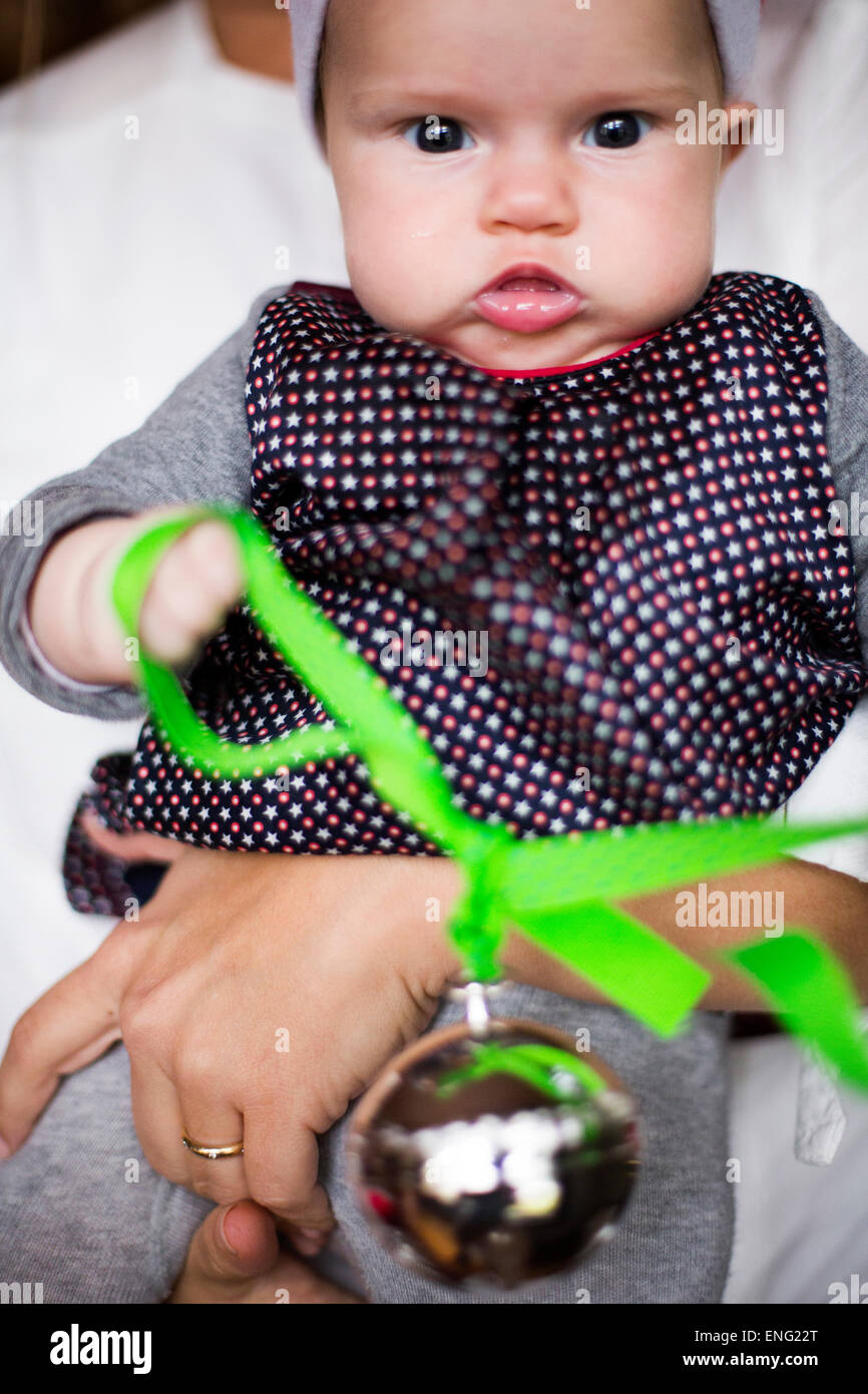 Close up of Caucasian baby girl holding Christmas ornament Stock Photo