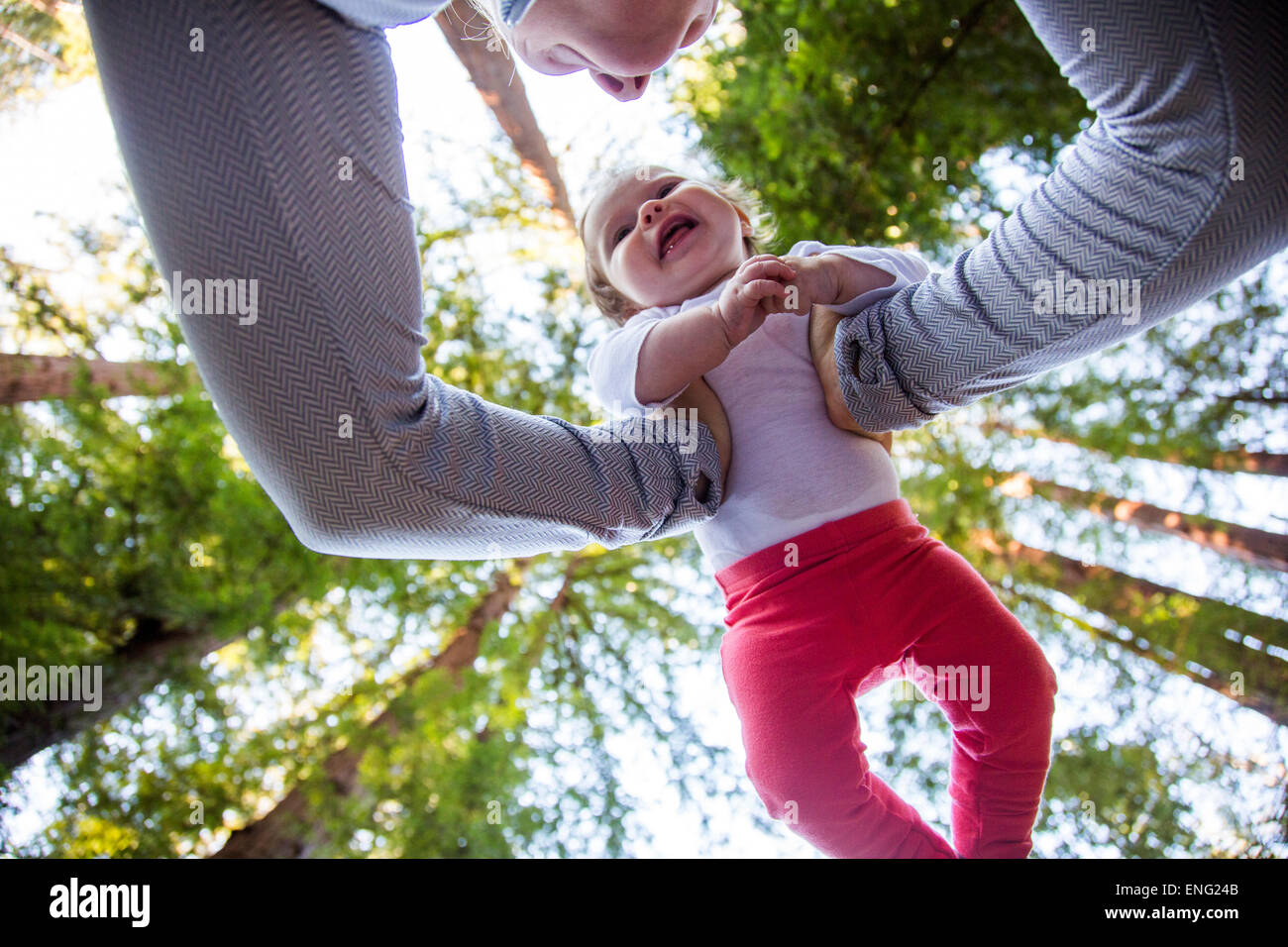 Low angle view of Caucasian mother playing with baby under trees Stock Photo