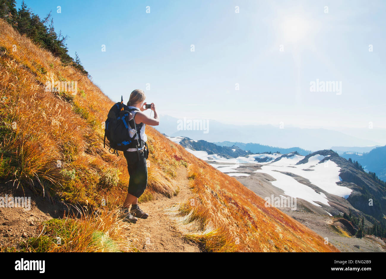 Woman taking photograph of remote mountains on hillside Stock Photo