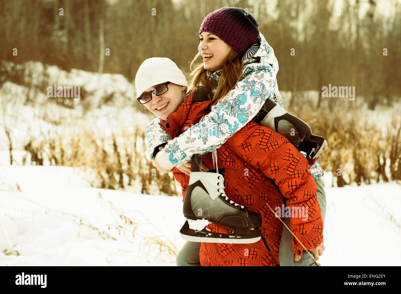 Caucasian couple carrying ice skates in snowy field Stock Photo
