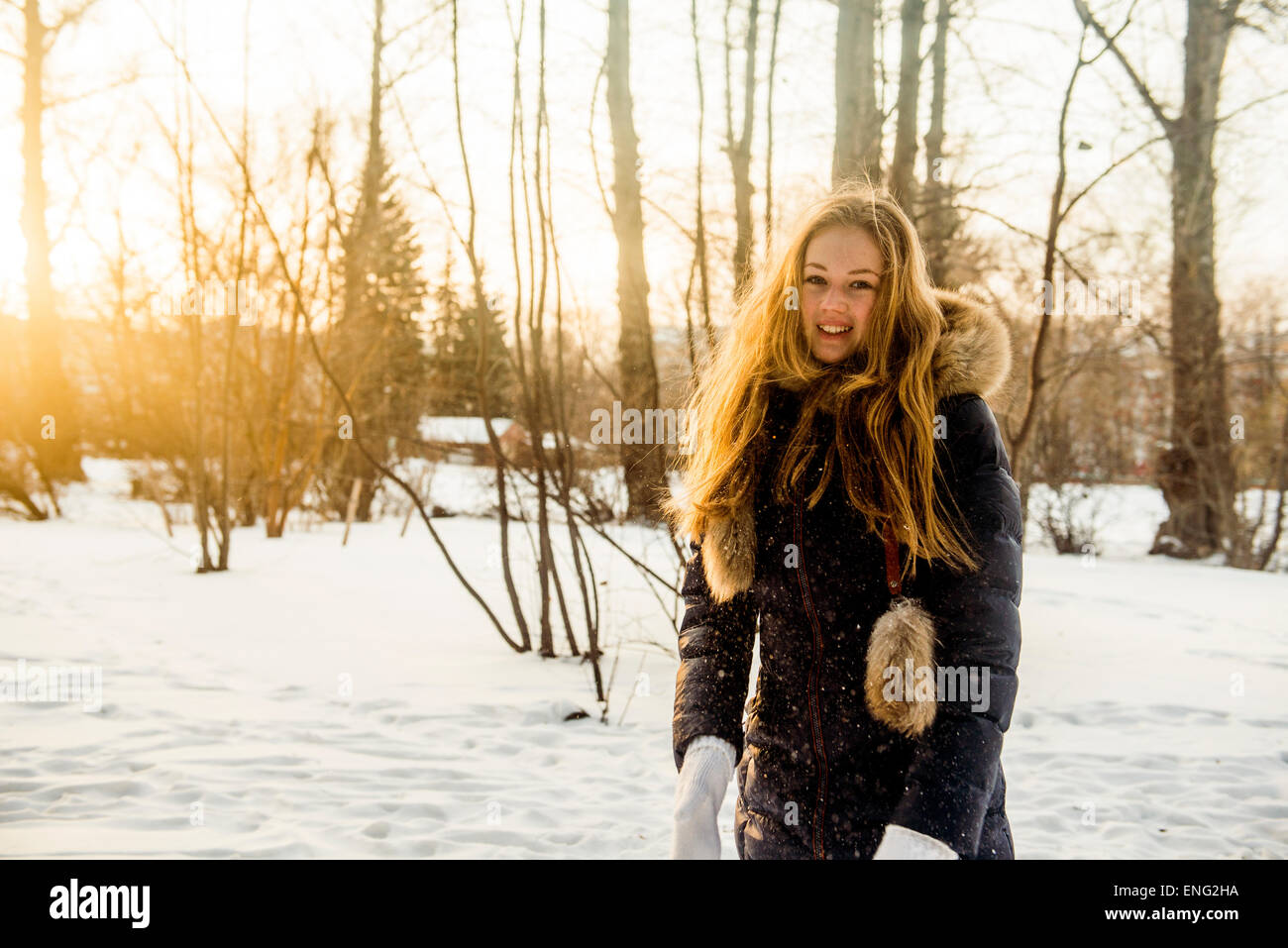 Caucasian woman playing in snowy field Stock Photo